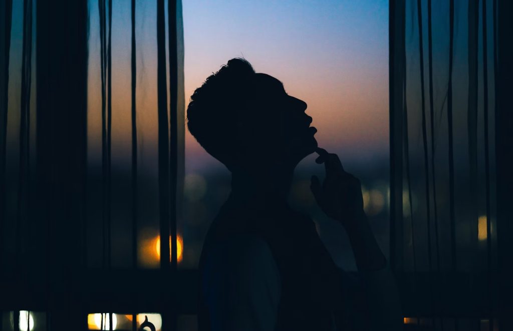 Man practicing a five-minute meditation by a window at twilight