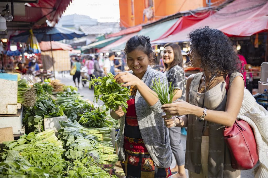 Filipino shopper choosing fresh vegetables at a public market while budgeting for nutritious family meals.