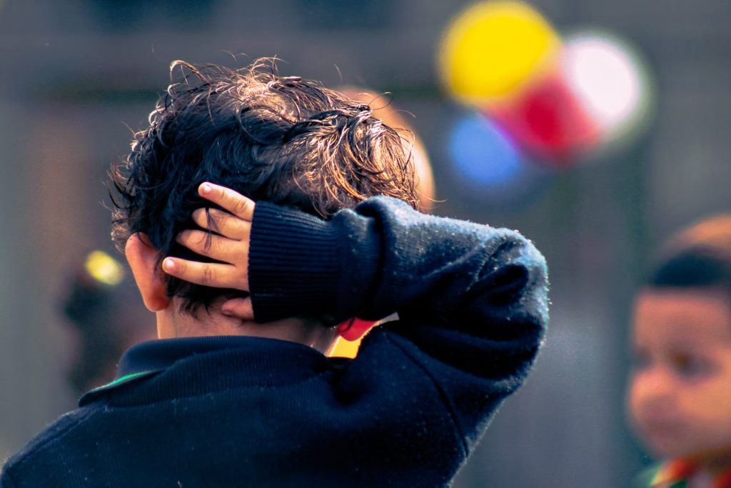 A child scratching his head, illustrating an article about understanding OCD, ADHD, and autism.